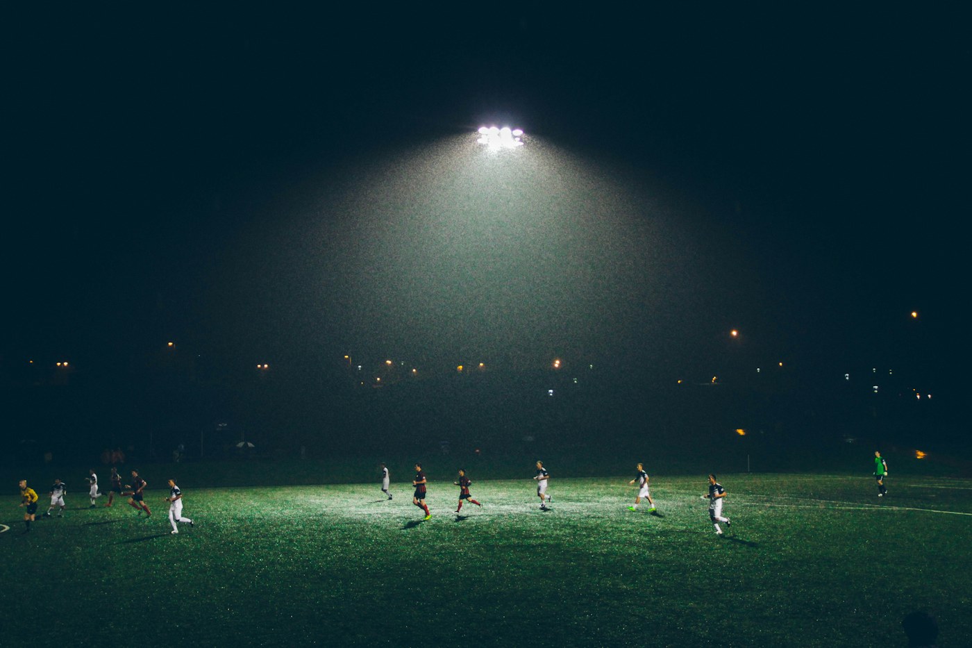 Partido de fútbol en un campo iluminado de noche